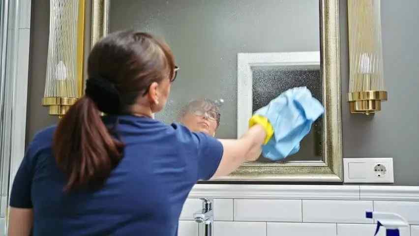 Professional cleaning services worker wiping down mineral-scaled mirrors in White Swan