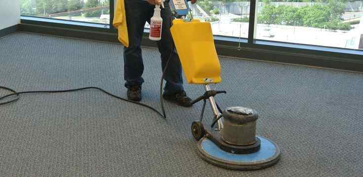 Commercial cleaning technician using a floor buffer machine to clean office carpets in Yakima.