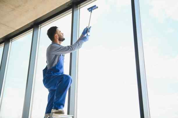 A professional cleaner from The Cleaning Brothers washing large windows in Yakima.