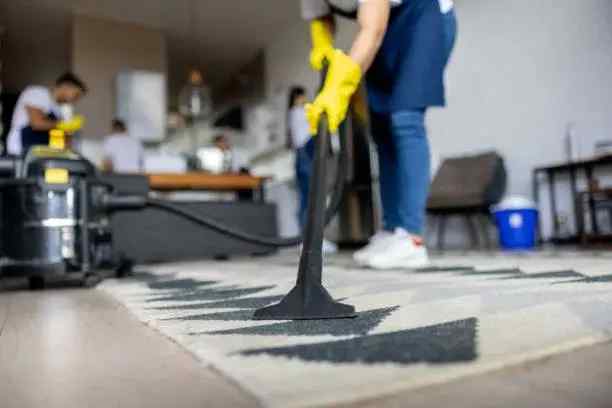 Professional cleaners vacuuming and deep cleaning a living room carpet in a Yakima home.